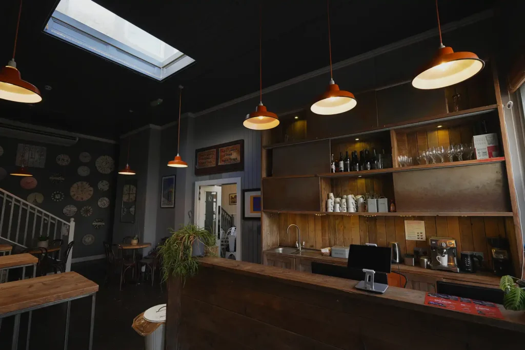 The cafe bar with its coffee machine, wooden counter and orange pendant lights